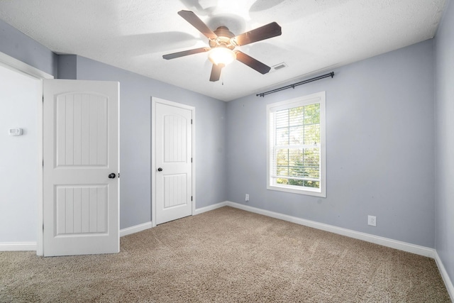 unfurnished room with a textured ceiling, ceiling fan, and carpet floors