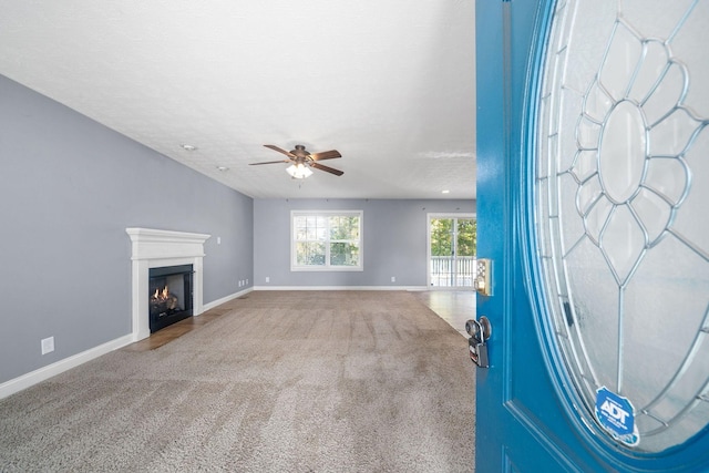 unfurnished living room featuring ceiling fan, a textured ceiling, and carpet flooring