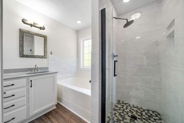 bathroom with hardwood / wood-style floors, vanity, a textured ceiling, and plus walk in shower