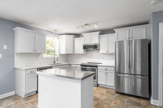 kitchen with stainless steel appliances, a center island, white cabinetry, and sink