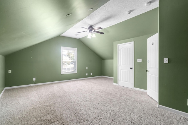 additional living space with ceiling fan, vaulted ceiling, a textured ceiling, and carpet flooring