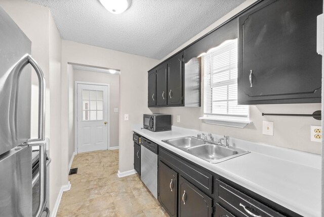 kitchen with a textured ceiling, stainless steel appliances, and sink