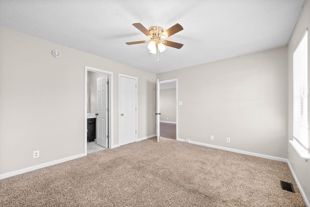 unfurnished bedroom with ceiling fan, light colored carpet, and connected bathroom