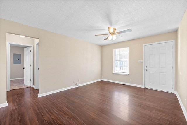 empty room with ceiling fan, dark hardwood / wood-style floors, a textured ceiling, and electric panel