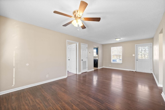 unfurnished living room featuring ceiling fan, dark wood-type flooring, and a textured ceiling