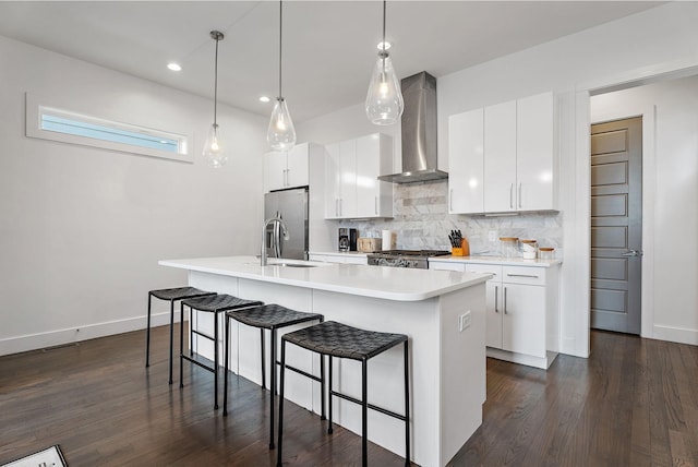 kitchen featuring sink, white cabinets, wall chimney exhaust hood, and a kitchen island with sink