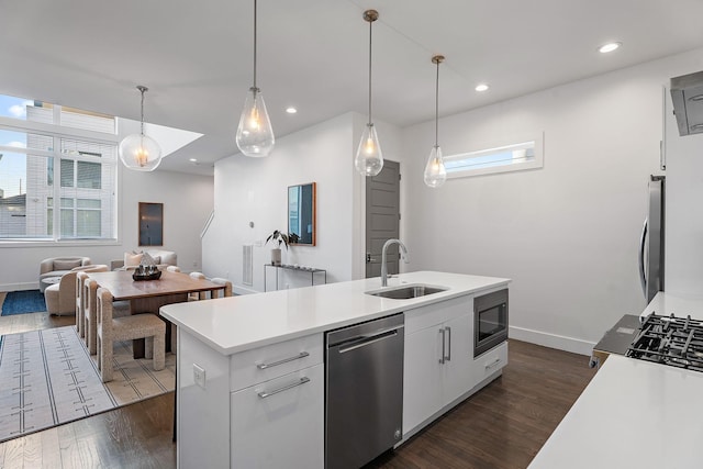 kitchen featuring pendant lighting, sink, a kitchen island with sink, appliances with stainless steel finishes, and white cabinets