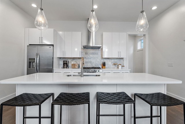 kitchen with an island with sink, backsplash, stainless steel fridge with ice dispenser, and white cabinetry