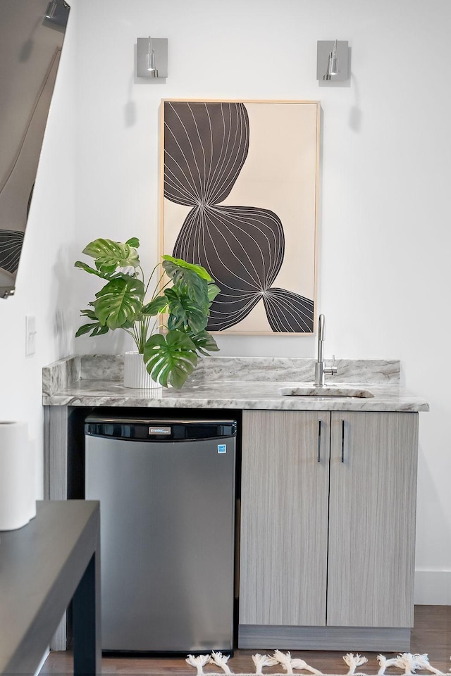 bar featuring sink, wood-type flooring, and refrigerator