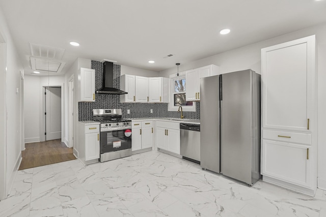 kitchen with stainless steel appliances, tasteful backsplash, wall chimney exhaust hood, white cabinets, and sink