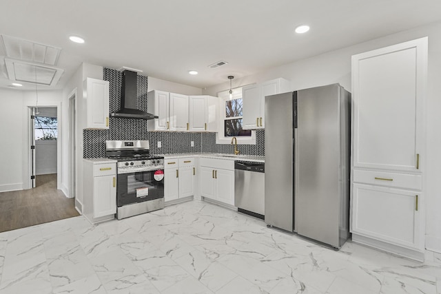 kitchen with appliances with stainless steel finishes, decorative light fixtures, wall chimney range hood, white cabinets, and sink