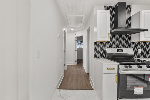 kitchen with stainless steel electric stove, white cabinets, wall chimney exhaust hood, and tasteful backsplash