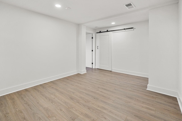 spare room with light wood-type flooring and a barn door