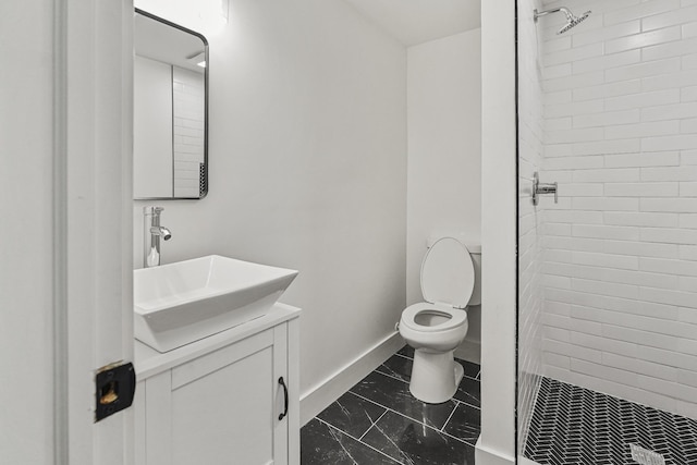 bathroom with toilet, vanity, and tiled shower