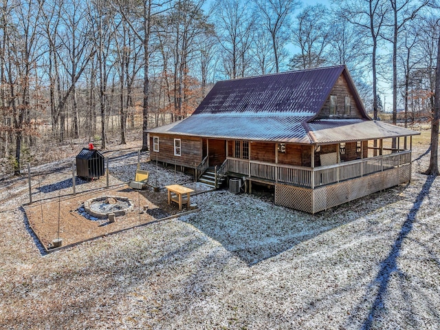 back of house with a porch, cooling unit, and a fire pit