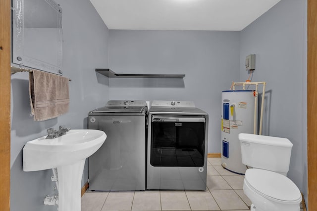 laundry room featuring water heater, sink, light tile patterned floors, and washer and clothes dryer