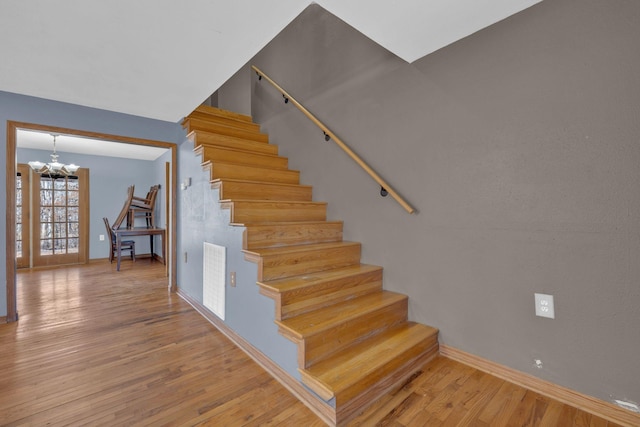 stairs with a notable chandelier and wood-type flooring