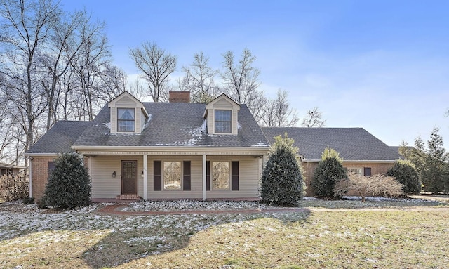 cape cod home featuring covered porch and a front yard