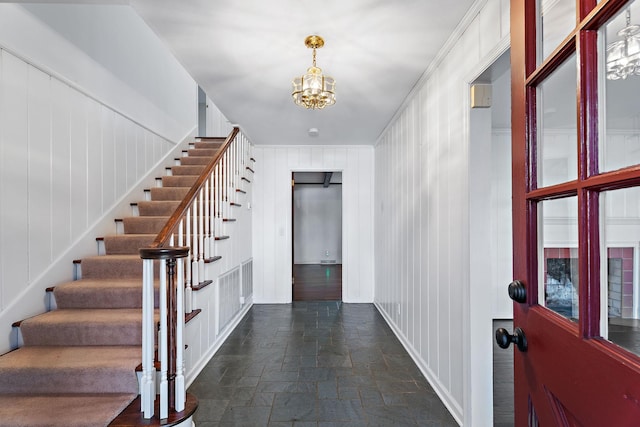 entryway featuring crown molding, wood walls, and a notable chandelier