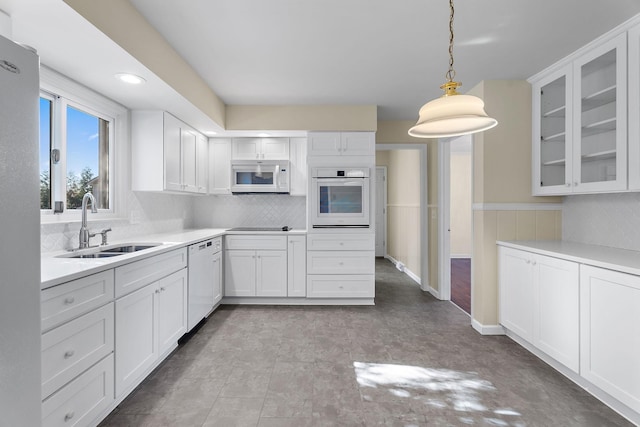 kitchen featuring pendant lighting, decorative backsplash, sink, white appliances, and white cabinetry