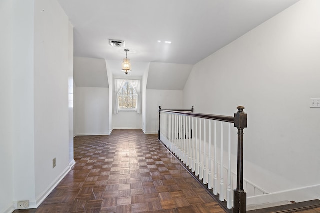 corridor with dark parquet flooring and vaulted ceiling