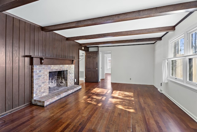 unfurnished living room featuring a fireplace, beamed ceiling, wooden walls, and dark hardwood / wood-style floors