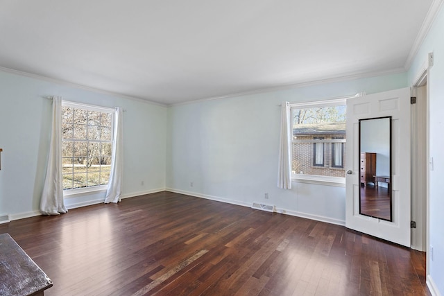 spare room featuring dark wood-type flooring, a wealth of natural light, and crown molding