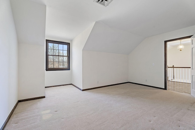 additional living space featuring light colored carpet and vaulted ceiling