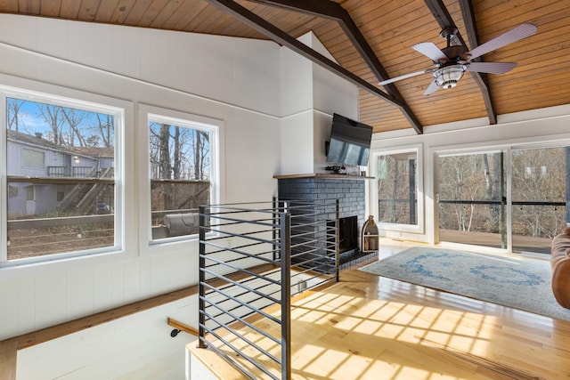 unfurnished sunroom with ceiling fan, vaulted ceiling with beams, a brick fireplace, and wooden ceiling