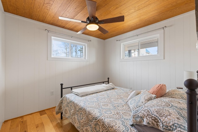 bedroom with ceiling fan, light hardwood / wood-style floors, wood walls, and wooden ceiling