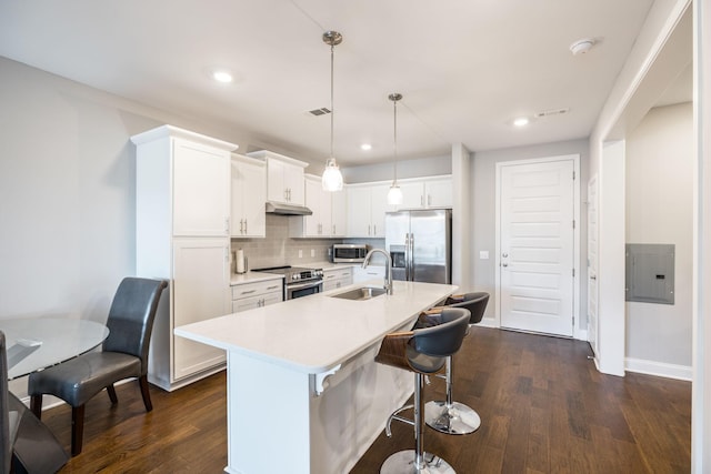 kitchen with stainless steel appliances, a kitchen island with sink, decorative light fixtures, white cabinets, and sink