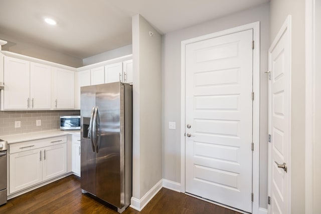 kitchen featuring dark wood-type flooring, appliances with stainless steel finishes, decorative backsplash, and white cabinetry