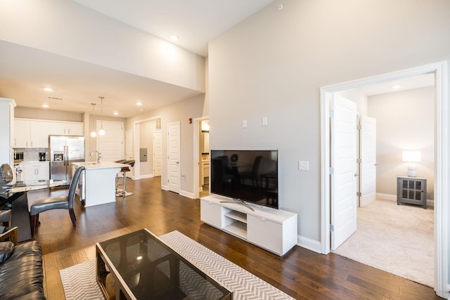 living room with dark hardwood / wood-style flooring, a high ceiling, and sink