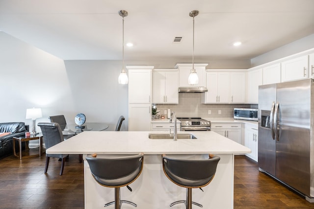 kitchen with stainless steel appliances, tasteful backsplash, decorative light fixtures, white cabinets, and sink