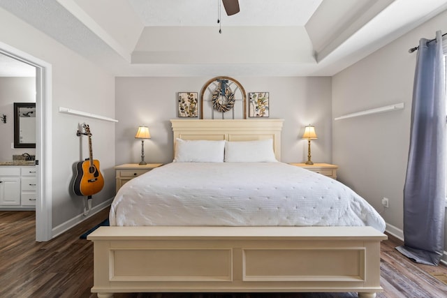 bedroom featuring ceiling fan, a raised ceiling, dark wood-type flooring, and ensuite bath