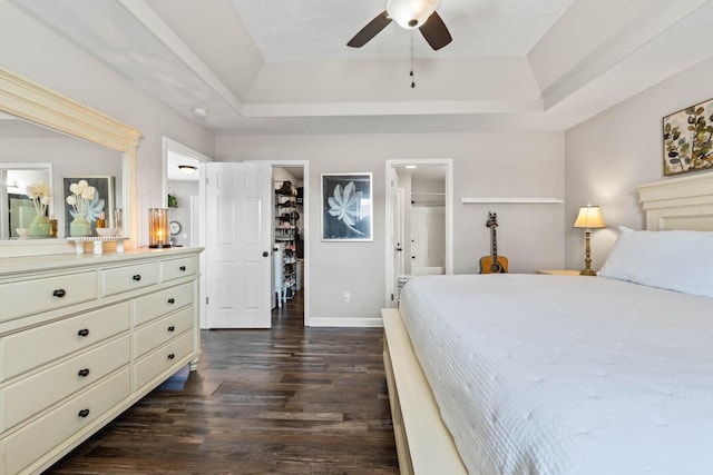 bedroom with a walk in closet, a closet, a raised ceiling, ceiling fan, and ensuite bathroom