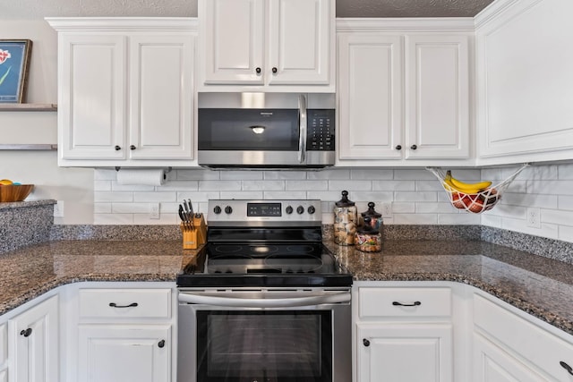 kitchen with decorative backsplash, white cabinets, appliances with stainless steel finishes, and dark stone countertops