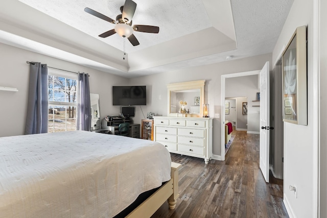 bedroom featuring ceiling fan, dark wood-type flooring, a textured ceiling, and a raised ceiling