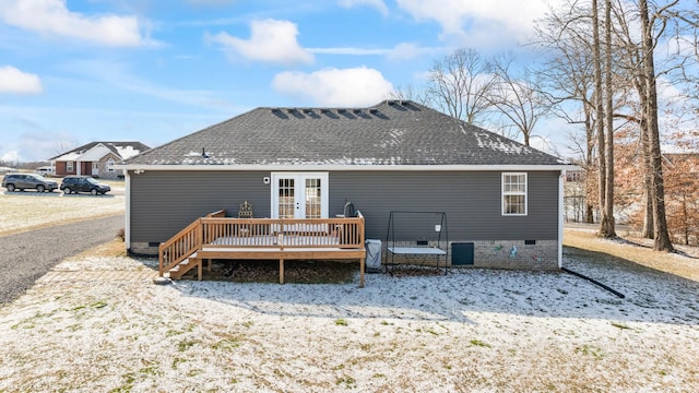 snow covered rear of property with a deck and french doors