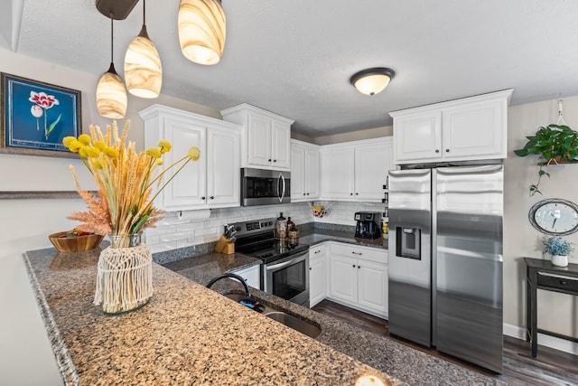 kitchen featuring white cabinets, stainless steel appliances, decorative backsplash, and decorative light fixtures