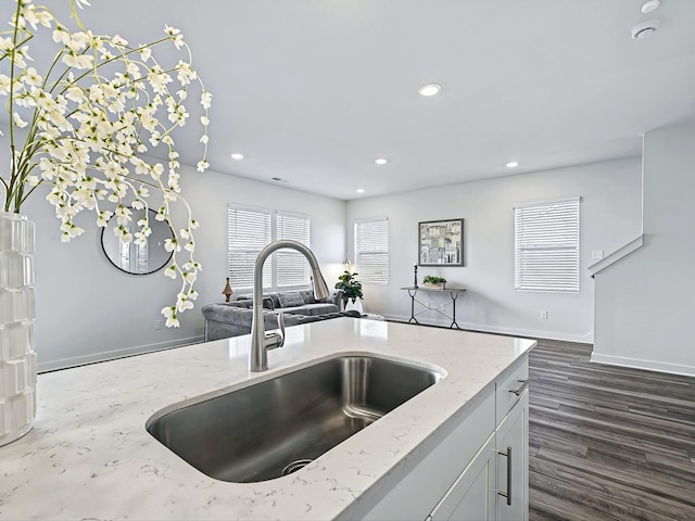 kitchen with white cabinetry, dark hardwood / wood-style floors, light stone countertops, and sink