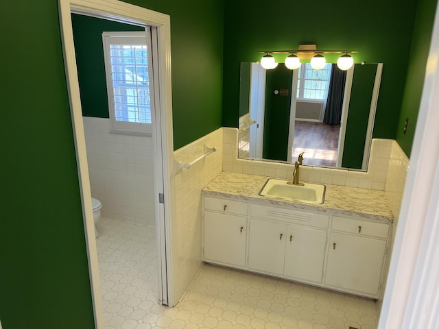 bathroom with toilet, tile walls, and vanity