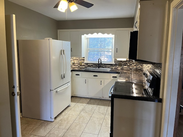 kitchen with electric range oven, sink, white refrigerator, and white cabinetry