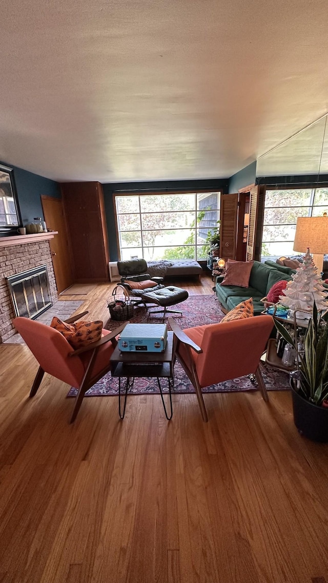 living room featuring light wood-type flooring, a textured ceiling, and a fireplace