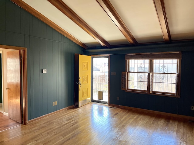 unfurnished room featuring light wood-type flooring and vaulted ceiling with beams