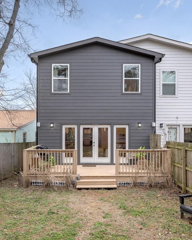 back of property with a wooden deck and a lawn