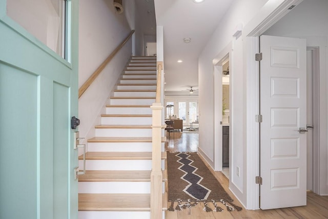 staircase with wood-type flooring and ceiling fan