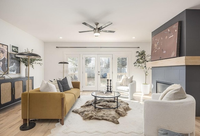 living room with ceiling fan, light hardwood / wood-style floors, french doors, and a tile fireplace