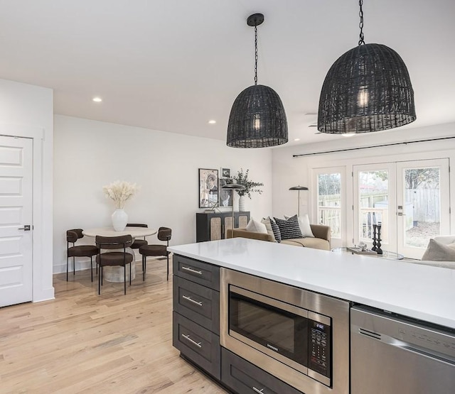 kitchen with stainless steel appliances, pendant lighting, and light wood-type flooring