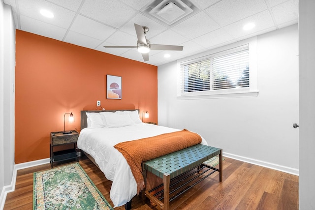 bedroom featuring ceiling fan, a drop ceiling, and hardwood / wood-style floors